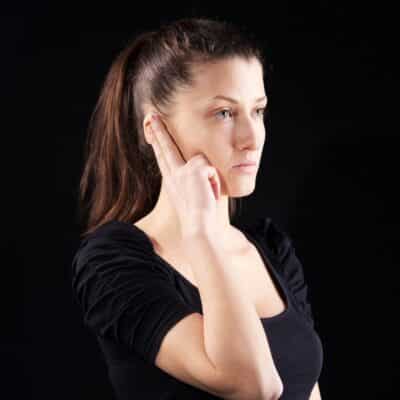 Woman touching her ear with a concerned expression