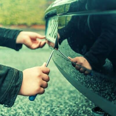 Person using screwdriver to remove a car license plate