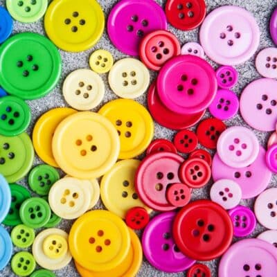Colorful assortment of buttons in various sizes on a textured surface