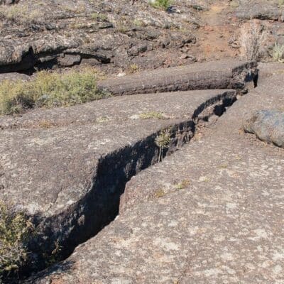 Narrow crevice running through rocky terrain with sparse vegetation