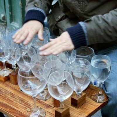 Person playing a glass harp using water-filled wine glasses