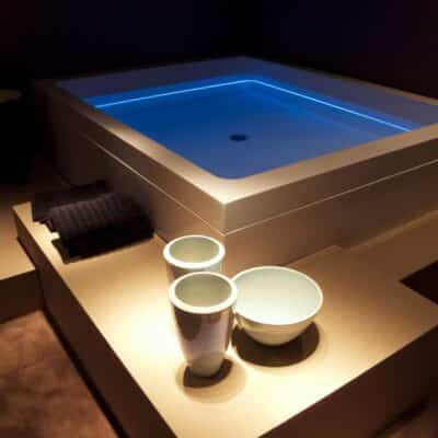 Modern Jacuzzi tub with glowing blue light and ceramic bowls nearby