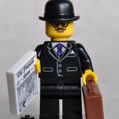LEGO minifigure in a suit holding a newspaper and briefcase