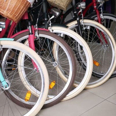 Close-up of several colorful bicycles with wicker baskets lined up indoors