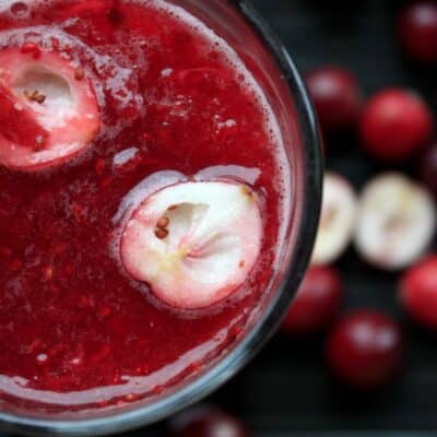 Close-up of cranberry cocktail with halved cranberries and seeds visible