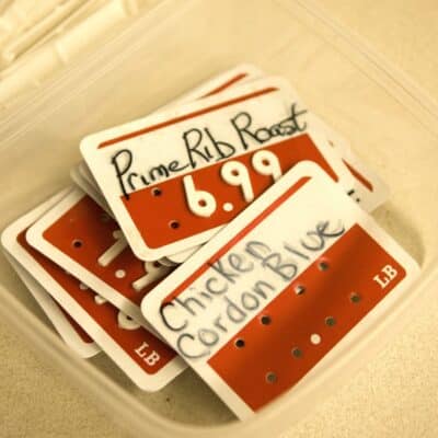 Plastic price tags labeled Prime Rib Roast and Chicken Cordon Blue in a container