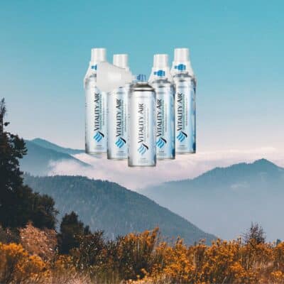 Cans of Vitality Air displayed over a scenic mountain landscape