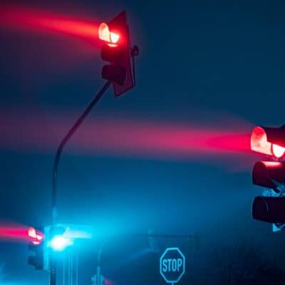 Multiple red traffic lights glowing at night near a stop sign