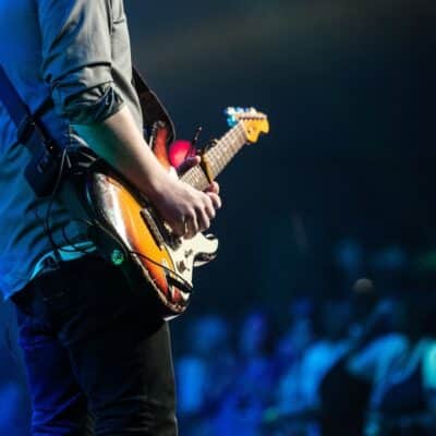 Guitarist playing electric guitar on stage in front of a crowd