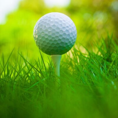 Golf ball on a tee surrounded by green grass