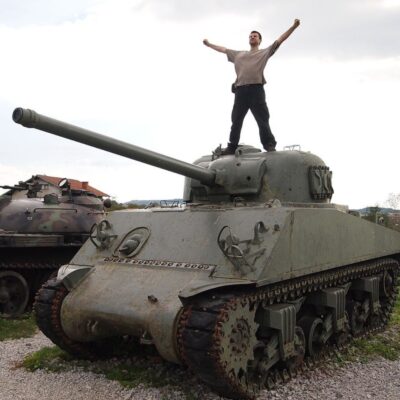 Man standing with raised arms on top of a military tank