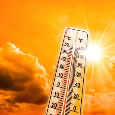 Thermometer showing high temperatures against bright sun and orange sky