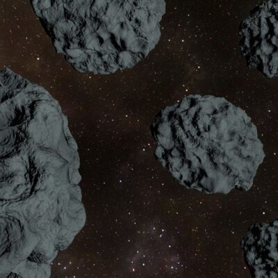 Several dark, rocky asteroids floating in outer space against a starry background