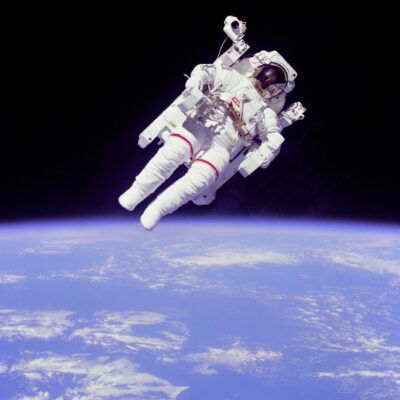 Astronaut in a white spacesuit floating above Earth with space in the background