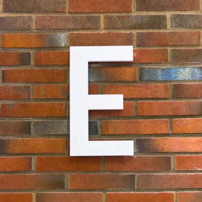 Large white letter E mounted on a brick wall