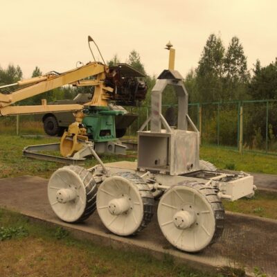 STR-1 robot with six wheels and metal frame on display near forested area