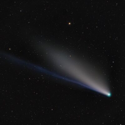Bright comet with glowing tail streaking across star-filled night sky