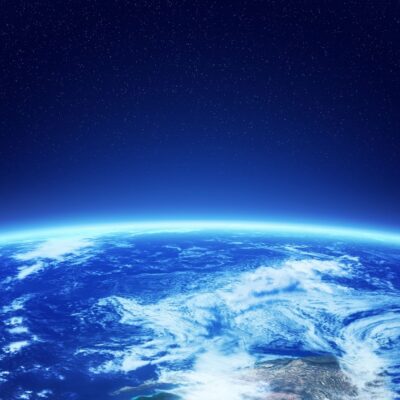 View of Earth’s atmosphere and surface from space with starry background