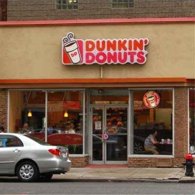 Dunkin’ Donuts storefront with customers inside and a car parked outside