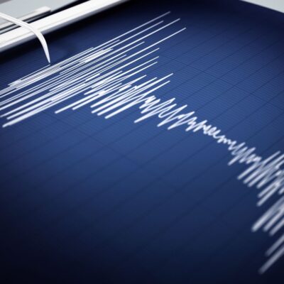 Seismograph recording with white waveform lines on blue graph paper