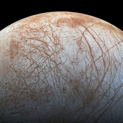 Europa’s icy surface with reddish-brown cracks and streaks