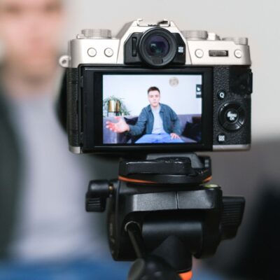 Man filming himself talking on camera while seated indoors