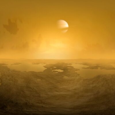 Hazy orange landscape of Titan with Saturn visible in the sky