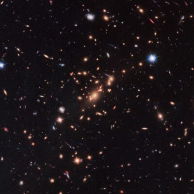 Dense cluster of galaxies with glowing stars and faint galaxies in deep space