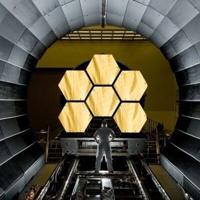 Engineer standing before James Webb Space Telescope’s gold-coated mirror segments