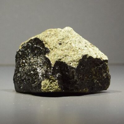 Chunky black and tan Martian meteorite displayed on a flat surface
