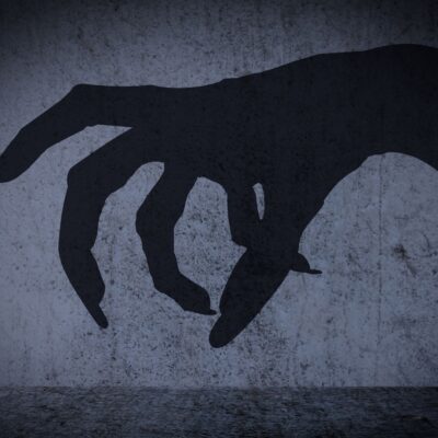 Shadow of a large clawed hand against a concrete wall