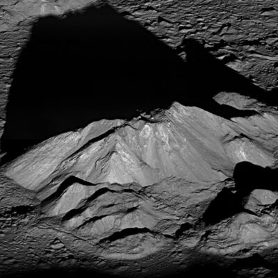 Mountain peak on the Moon partially illuminated with surrounding deep shadows