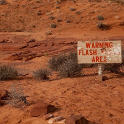Desert landscape with worn warning sign for flash flood area
