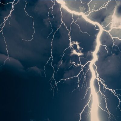Bright lightning bolts streak across a dark, stormy sky