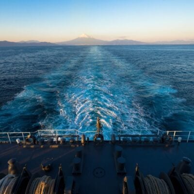 Ship sailing away from shore with Mount Fuji visible in the distance