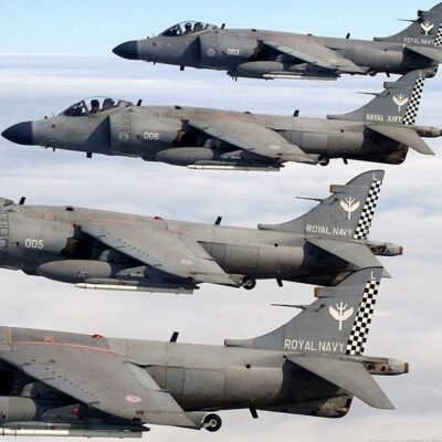 Four Royal Navy Sea Harrier jets flying in close formation above clouds