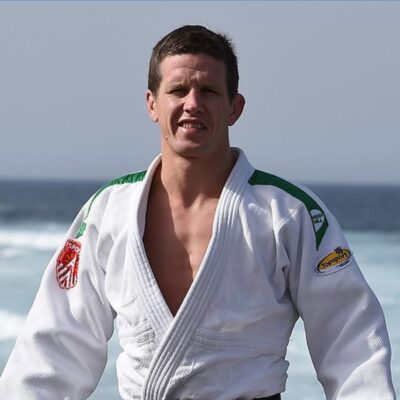 Dirk Van Tichelt in a judo gi standing by the ocean