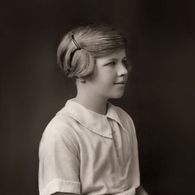 Young Venetia Burney in a light-colored dress, looking to the side