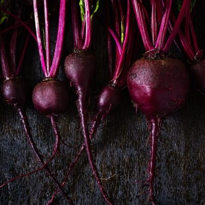 Fresh whole beetroots with stems on a dark wooden surface