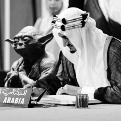 Yoda from Star Wars, seated next to King Faisal of Saudi Arabia, at a formal event.