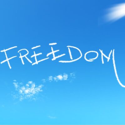 The word 'FREEDOM' written in white smoke across a clear blue sky