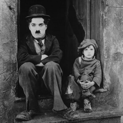 Charlie Chaplin and Jackie Coogan sitting on a doorstep in a scene from The Kid