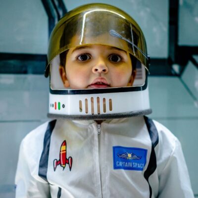 Young child in a toy astronaut suit with helmet and Captain Space badge