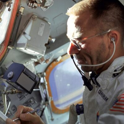 Astronaut in a spacecraft writing with a pen near a window