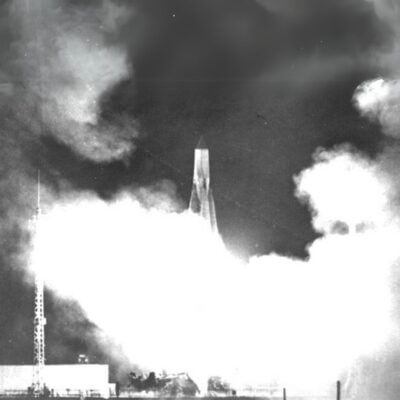 Sputnik 1 launch vehicle lifting off with smoke and flames at night