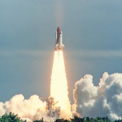 Space shuttle launching with bright flames and smoke below