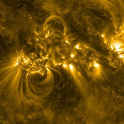 Swirling yellow plasma arcs and sunspots on the surface of the Sun