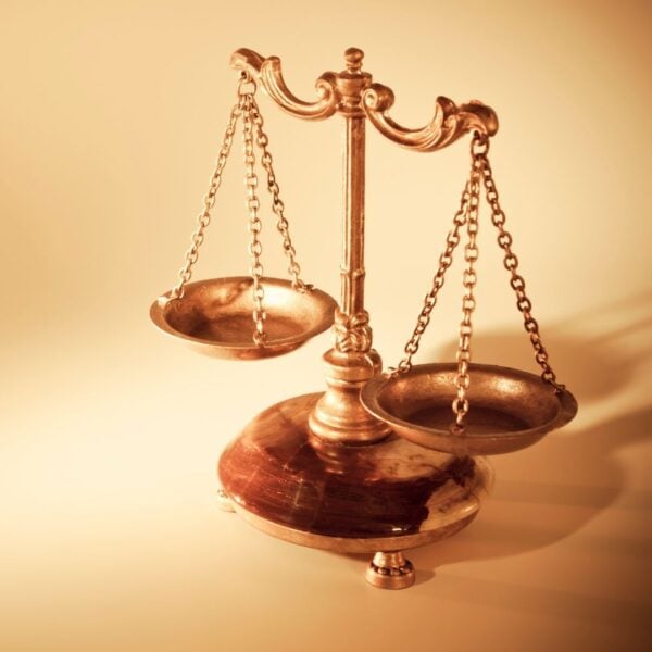 Bronze balance scale with unevenly weighted pans on a marble base