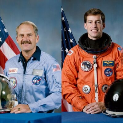 James van Hoften and James Wetherbee in NASA uniforms with American flags behind them