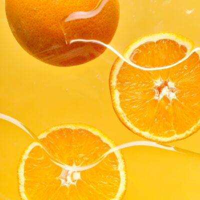 Whole orange floating and orange slices submerged in yellow water